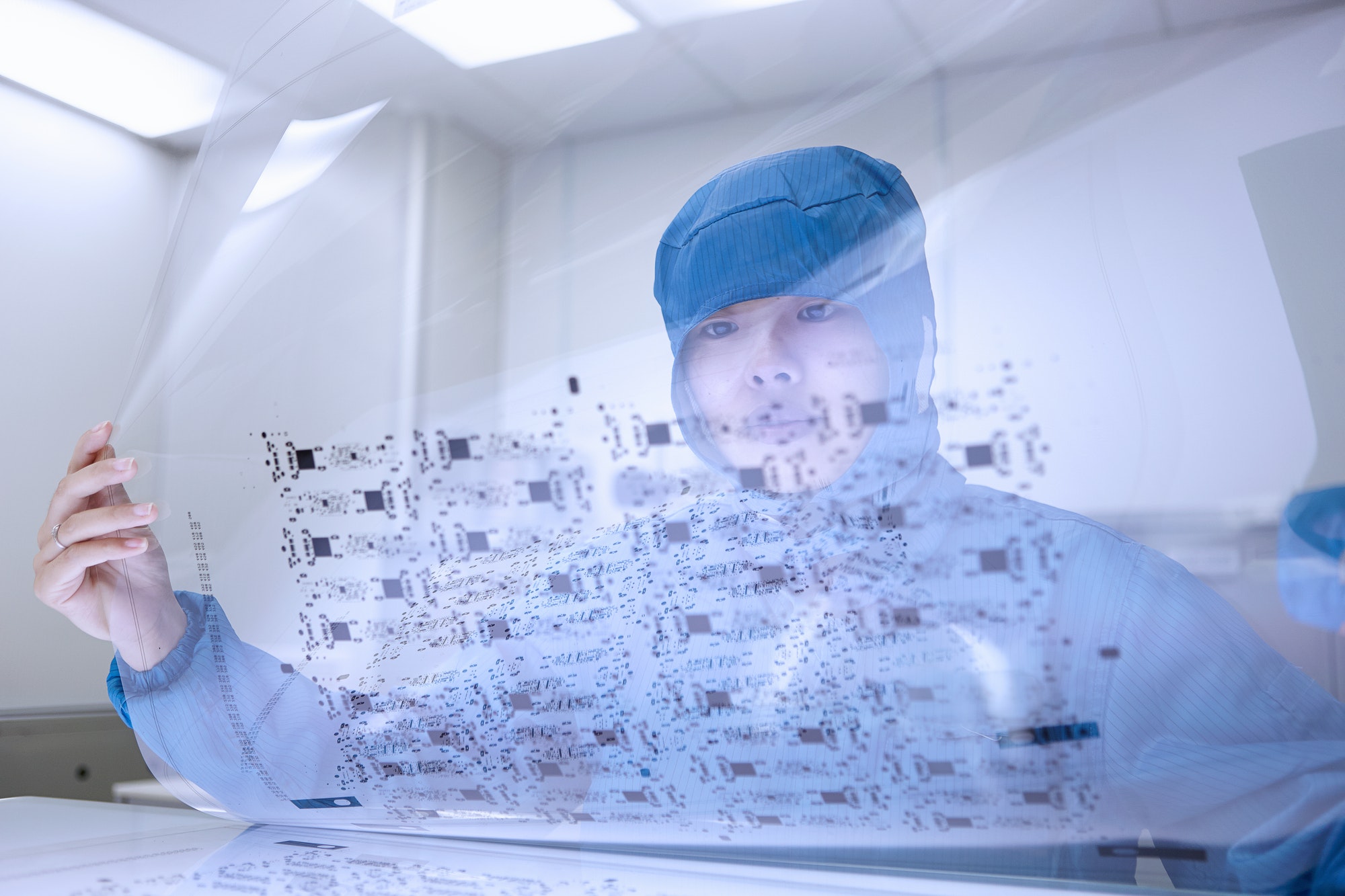 Female worker holding flex circuit in flexible electronics factory clean room